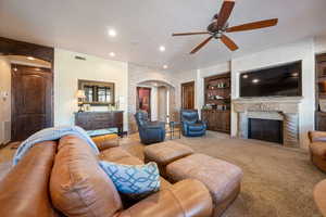 Carpeted living room with ceiling fan, a high end fireplace, built in features, and a textured ceiling