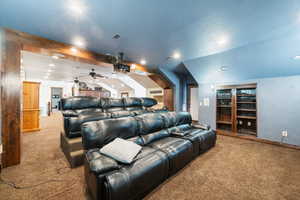 Carpeted home theater with vaulted ceiling