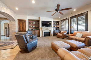 Living room featuring ceiling fan, built in features, and a textured ceiling