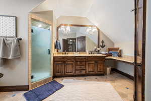 Bathroom featuring walk in shower, lofted ceiling, an inviting chandelier, vanity, and tile patterned flooring