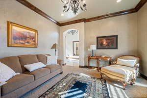 Carpeted living room featuring ornamental molding and a notable chandelier