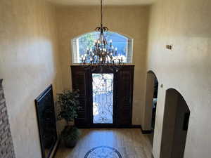 Entryway with an inviting chandelier, a towering ceiling, and light hardwood / wood-style flooring