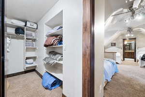 Spacious closet with light carpet and ceiling fan