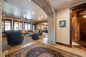 Living room featuring ceiling fan, decorative columns, and a textured ceiling