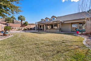 Rear view of house with a yard and a patio