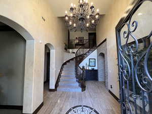 Entryway featuring hardwood / wood-style flooring, a chandelier, and a high ceiling