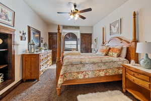 Bedroom featuring ceiling fan, a textured ceiling, and dark colored carpet