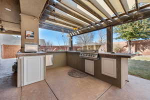 View of patio featuring area for grilling, a pergola, an outdoor bar, and exterior kitchen