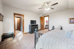 Bedroom featuring ceiling fan, lofted ceiling, and carpet flooring