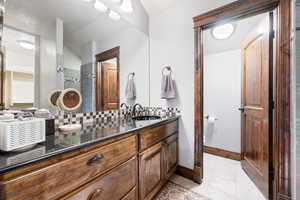 Bathroom featuring tiled shower, tile patterned floors, vanity, and backsplash