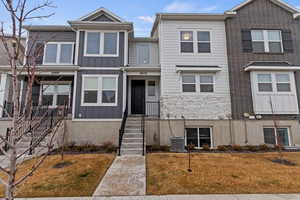 View of property with central AC and a front lawn