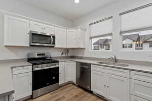 Kitchen with stainless steel appliances, white cabinetry, and sink