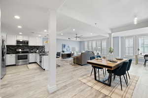 Dining room featuring light wood-type flooring, ceiling fan, sink, and ornate columns