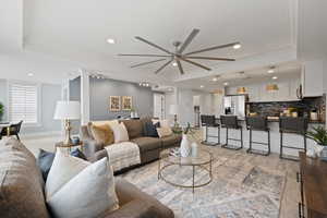 Living room with ornamental molding, light hardwood / wood-style flooring, ceiling fan, and a tray ceiling