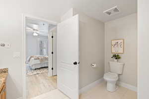 Bathroom with tile patterned flooring, vanity, ceiling fan, and toilet