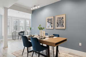 Dining space featuring track lighting, light hardwood / wood-style floors, and ornate columns