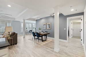 Dining area featuring ornate columns, a raised ceiling, crown molding, track lighting, and light wood-type flooring