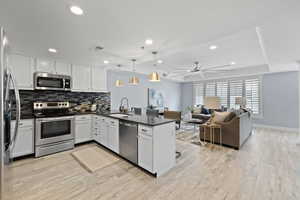 Kitchen featuring sink, white cabinetry, hanging light fixtures, stainless steel appliances, and kitchen peninsula