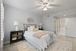 Bedroom with ceiling fan, ensuite bathroom, and light hardwood / wood-style floors