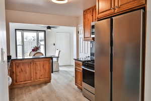 Kitchen with ceiling fan, stainless steel appliances, and light hardwood / wood-style floors