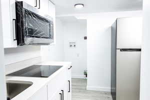 Kitchen featuring light wood-type flooring, appliances with stainless steel finishes, sink, and white cabinets