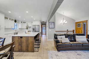 Kitchen featuring sink, decorative light fixtures, a center island, stainless steel appliances, and white cabinets