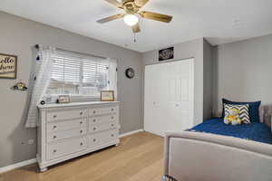 Bedroom with ceiling fan, a closet, and light carpet