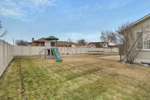 View of yard with a trampoline and a playground