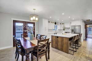 Dining area with sink, a chandelier, a textured ceiling, and light hardwood / wood-style flooring