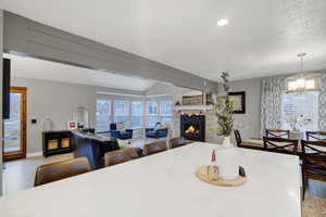 Dining room with lofted ceiling, a textured ceiling, a notable chandelier, and light wood-type flooring