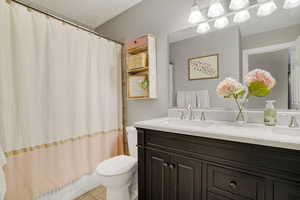 Bathroom with vanity, a textured ceiling, and toilet