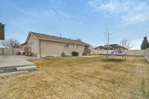 Rear view of property with a yard, a patio area, and a trampoline