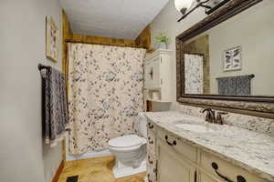 Bathroom with vanity, a textured ceiling, and toilet