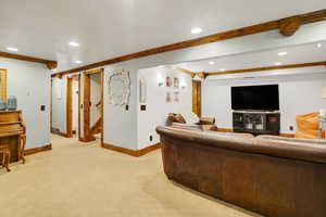 Living room with light colored carpet and beam ceiling