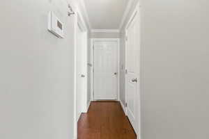 Corridor with crown molding and dark wood-style flooring