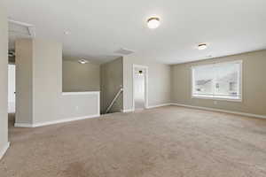 Carpeted empty room featuring baseboards and visible vents