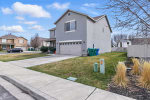 View of side of home featuring fence, a residential view, driveway, a garage, and a yard