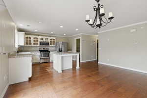 Kitchen featuring a chandelier, wood finished floors, a kitchen bar, appliances with stainless steel finishes, and a center island
