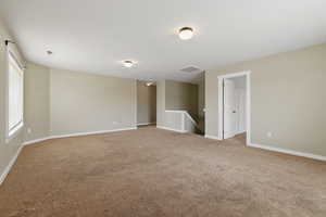 Empty room featuring baseboards, visible vents, and carpet flooring