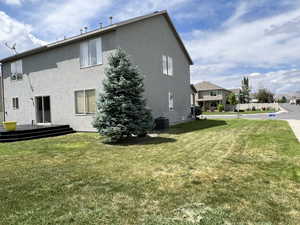 Back of house featuring a yard and central air condition unit
