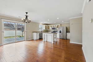 Kitchen with glass insert cabinets, appliances with stainless steel finishes, a chandelier, and wood finished floors