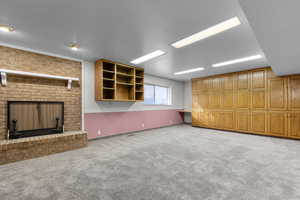 Downstairs family room with light colored carpet, a textured ceiling, and a fireplace
