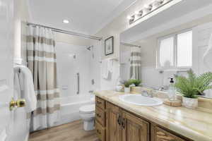 Full bathroom with vanity, shower / tub combo, wood-type flooring, and toilet