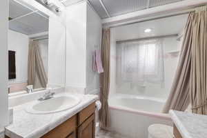 Full bathroom featuring shower / bathtub combination with curtain, vanity, and toilet