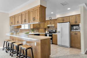 Kitchen with built in microwave, stainless steel range with electric cooktop, a kitchen bar, white fridge with ice dispenser, and kitchen peninsula