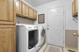 Laundry room featuring light tile patterned flooring, cabinets, and washing machine and dryer