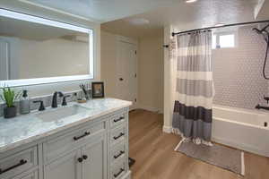 Bathroom with vanity, wood-type flooring, a textured ceiling, and shower / tub combo with curtain