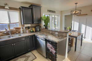 Kitchen featuring sink, tasteful backsplash, decorative light fixtures, stainless steel dishwasher, and kitchen peninsula