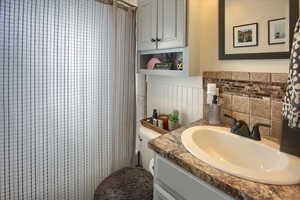 Bathroom with vanity, tasteful backsplash, and toilet