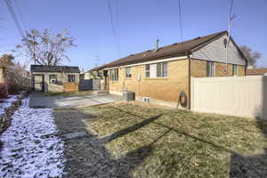 Snow covered property featuring a storage shed, a yard, a patio, and central AC unit